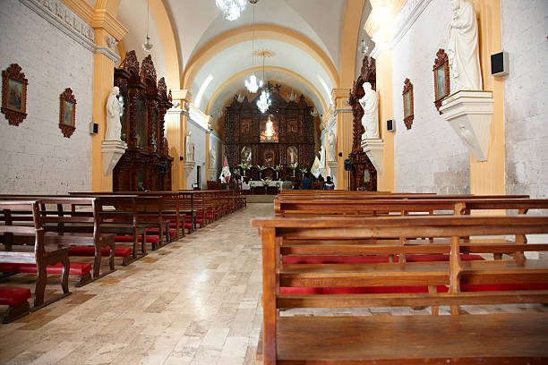 Arequipa, Peru - May 26, 2013: Pews in the back of an Arequipa church. People are pictured praying at the front of the building