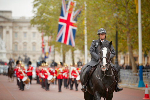 London, United Kingdom - October 25, 2012: Policewoman on the horse behind marching the Queen's Guards during traditional Changing of the Guards ceremony at Buckingham Palace on October 25, 2012 in London, United Kingdom.