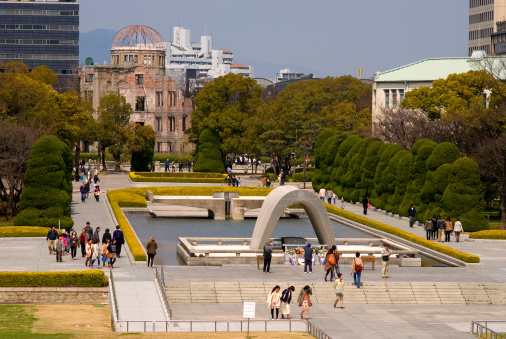 Hiroshima, Japan - April 16, 2011: Peace memorial and the A-Bomb Dome in Hiroshima. The A-Bomb Dome was an office building and one of thos few ones which have survived the Hiroshima nuclear attack in August 6, 1945. The Peace memorial Park have been built there later to remember the victims. People visit the park daily. The park is in front of the ruins of the A-Bomb Dome.