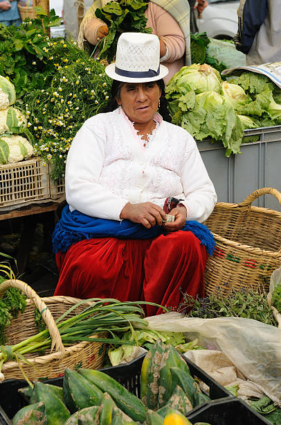 Quito, Pichincha, Ecuador - April 14, 2022: Indigenous ecuadorian woman wearing a face mask and traditional clothing carrying a tray with food during a Holy Week procession in the historic center of Quito, Ecuador