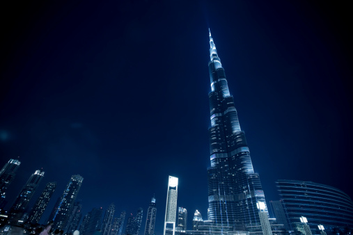Dubai, United Arab Emirates - March 24,2013 : The iconic spire of the Burj Khalifa, the world's tallest building, illuminated against the blue dusk sky.