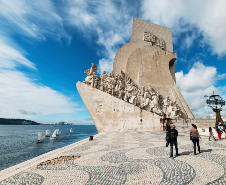 Lisbon, Portugal - March 17, 2013: Monument of the Discoveries in Lisbon, Portugal, was inaugurated in 1960 by the Salazar Government. It is situated close to BAlem and overlooking the Tagus River. With an elevator inside the building you can reach a visitors platform on top of the building with a fantastic view over Belem and the Tagus River.Some turists watching the monument.