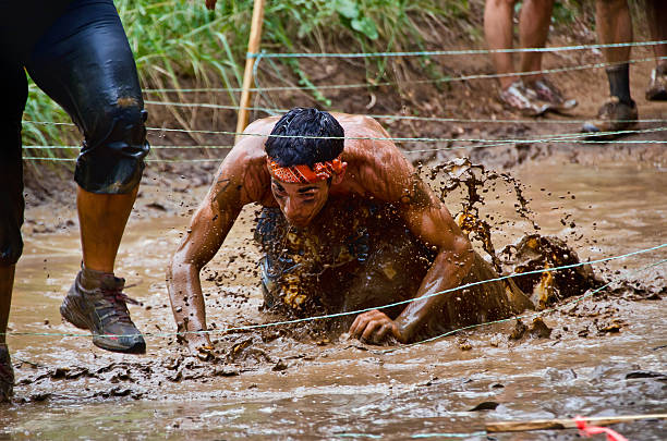 corrida na lama participante agachamento com fios - mud run - fotografias e filmes do acervo