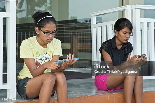 Dos Mujeres Jóvenes Verificar Mensajes De Texto En Ipad Y Iphone Foto de stock y más banco de imágenes de Adulto