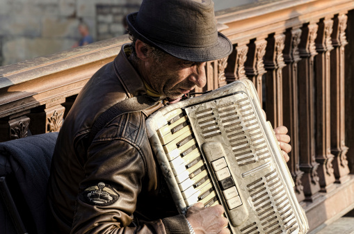 Paris, France &amp;ndash; May 25, 2012. Mature busker man playing accordion on bridge in Paris.