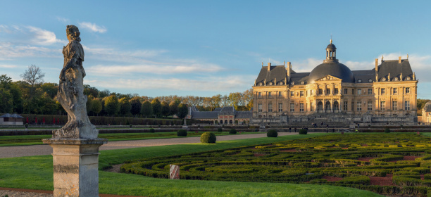 Vaux-le-Vicomte, France  - November 1, 2012: Vaux-le-vicomte castle is the most important one in France before Versailles in the 17th century. The image is a view of the castle from the garden with a statue on the left during an autumn evening