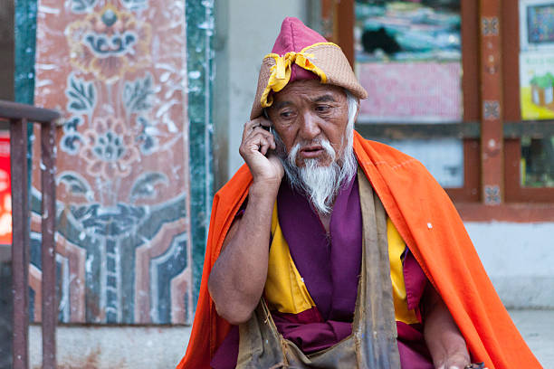 Old bhutanese monk making phone call in streets of Thimpu stock photo