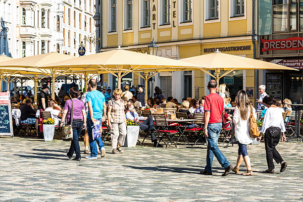 Dresden, Germany - September 06, 2013: Restaurant with many people in front of the famous Frauenkirche in Dresden. Pedestrians passing by and people sitting at the table in street cafe.