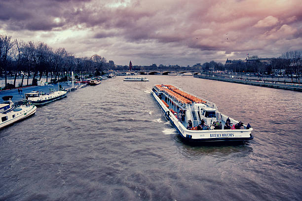 Paris, France  - December 27, 2012: Bateaux-Mouches with tourists on Seine River, Christmas in Paris, overcast winter day, big Christmas tree is visible on background.