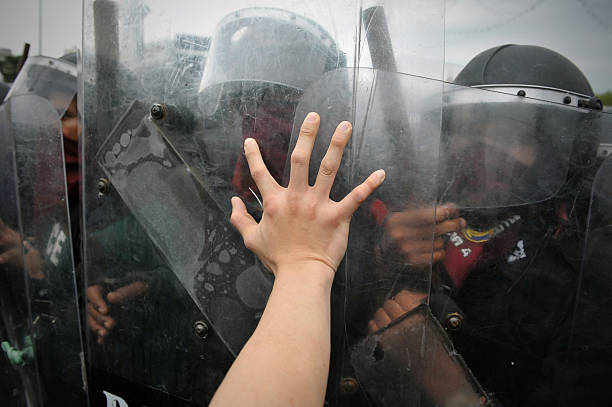 Anti-Government Rally in Bangkok Bangkok, Thailand - November 24, 2012: A protester from the nationalist Pitak Siam group pushes against a police riot shield during a large anti-government rally on Makhawan Bridge. peoples alliance for democracy stock pictures, royalty-free photos & images