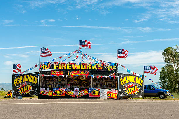 Roadside Fireworks Stand in Montana Bozeman, United States - July 1, 2013: A few days before the July 4th holiday, a fully stocked fireworks stand is open for business on the side of the road. American flags decorate the stand which boldly advertises TNT and Fireworks. Behind the stand is a parked blue pickup truck and open sky. firework explosive material photos stock pictures, royalty-free photos & images