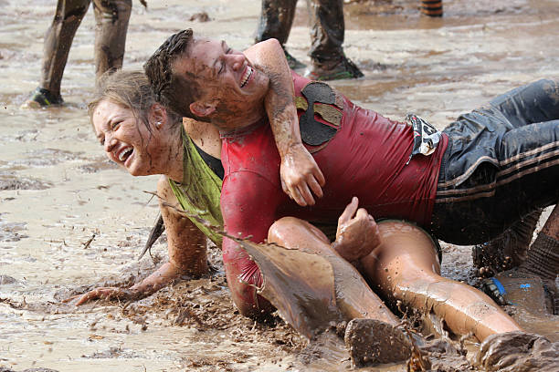 Two Mud Run participants wrestling stock photo