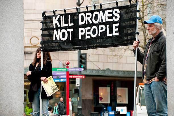 Anti Drone Protest Seattle, USA - April 17, 2013: Two people at West Lake Park holding a banner protesting the use of military drones. air attack stock pictures, royalty-free photos & images