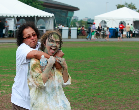 Ottawa, Canada - August 11, 2012: After participating in a holi celebration, Wendy Rockburn, stage manager, is hugged by a friend at the inaugural Festival of India in Ottawa, Ontario.