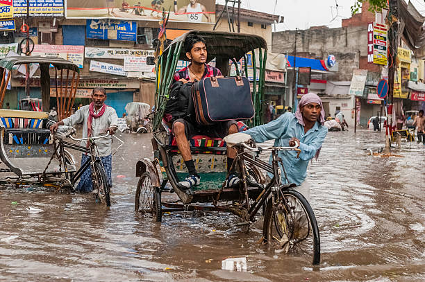 Flash flood during monsoon, Varanasi, India. Varanasi, India - August 11, 2011: cycle rickshaws and a passenger with a suitcase try to make headway through a central street in Varanasi despite the heavy monsoon rain and the increasingly risky rising water level as a result of the flash flood. monsoon stock pictures, royalty-free photos & images