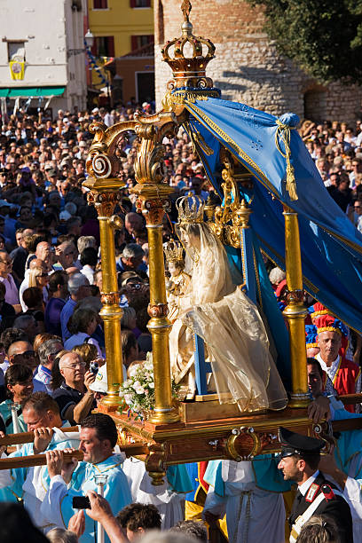 Caorle; religious procession Caorle, Italy - 12 september 2010: The statue of the Madonna is carried in procession by the pilgrims, after passing through the streets of the country comes to the marina, where it will be put on a boat to continue the procession at sea. monsignor stock pictures, royalty-free photos & images