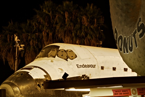 Los Angeles, USA: October 12, 2012 - The space shuttle Endeavor parks next to the giant donut of Randy's Donuts, a famous Los Angeles landmark at the corner of Manchester Blvd. and La Cienega Blvd.