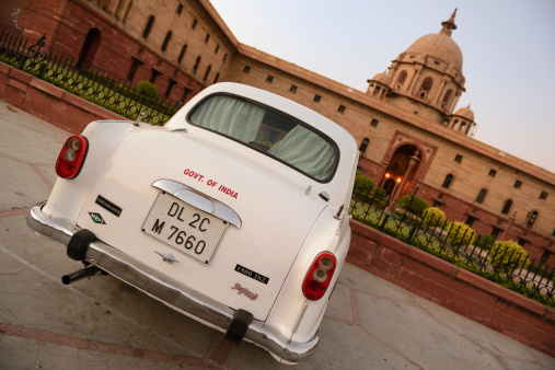 Delhi, India - October 2, 2012: Official governemental car parked in front of Indian Parliment in New Delhi. Late evening, high iso (grain).