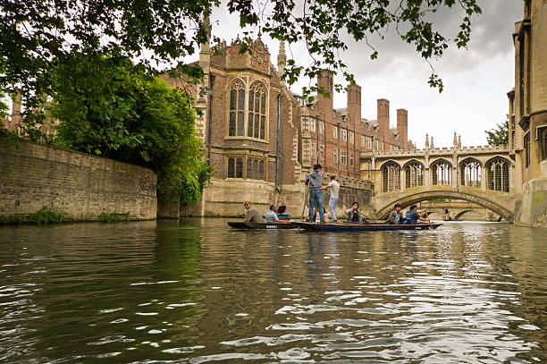 Punting on the Cam Cambridge, United Kingdom - June 16, 2013: Lazy Sunday afternoon on the River Cam in Cambridge, England, tourists on punts with tourists looking on. couple punting stock pictures, royalty-free photos & images