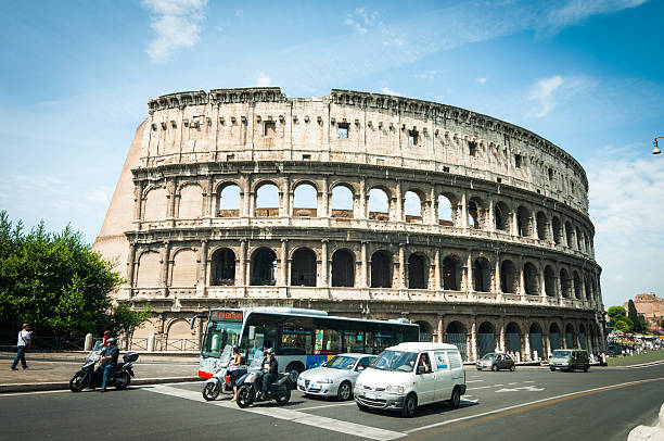 ROME, Italy - June 6, 2011:  The Colosseum at day time, while traffic is running along via Dei Fori Imperiali in the centre of town.