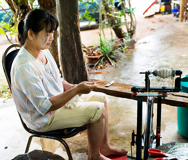 Thai Woman Spinning Silk stock photo