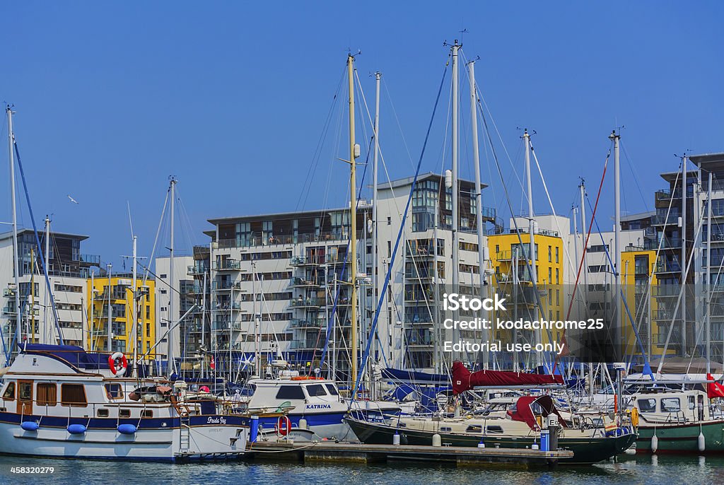 marina Eastbourne, UK - July 7, 2013: The location is the Sovereign Harbour Marina, on the South Coast of England at the seaside resort of Eastbourne in Sussex. Boats are moored surrounded by flats and apartments. There are motor boats, fishing boats and sailing yachts at their moorings, It is a hot sunny day in July, Summer and there is a clear blue sky. The Marina is popular with tourists visitors and leisure boaters. Apartment Stock Photo