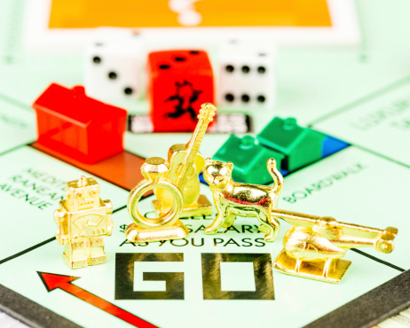 Suffolk, Virginia, USA - September 29, 2013: A square format studio shot of a Monopoly game board with five tokens on the GO position. The tokens include a robot, engagement ring, a guitar, cat and a helicopter. The tokens were introduced by Hasbro as potential replacement to one of the older pieces, the iron. The decision on the new token was determined by fan votes, and the new piece introduced was the cat token.
