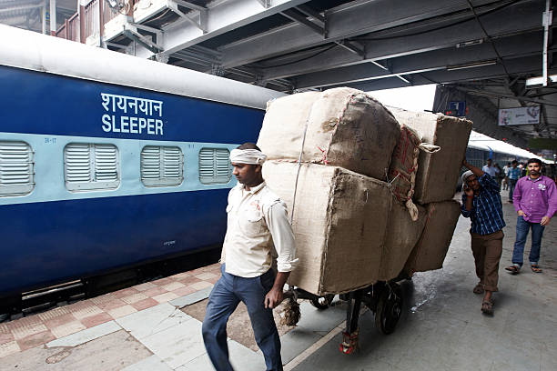 porters tirant grand chariot à roulettes à la gare ferroviaire de varanasi - baggage wagon photos et images de collection
