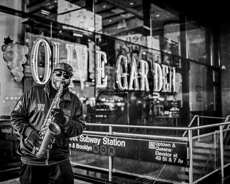 New York City, USA - April 18, 2013: A saxophonist playing his instrument in front of the Olive Garden restaurant on Midtown 7th Avenue, right next to the subway station entrance.