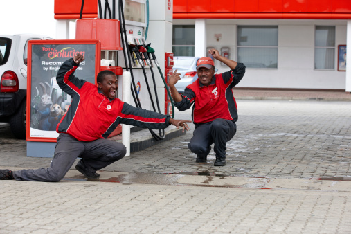 Mossel Bay, South Africa - February 8, 2012: Two male gas station attendants in colorful uniforms try to impress to attract customers and tips at a gas station forecourt in Mossel Bay, South Africa