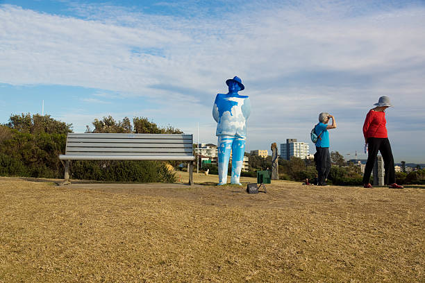 Sydney, Australia - October 30, 2012: Two women walk beside a sculpture of a man by artist Stephen Marr titled \