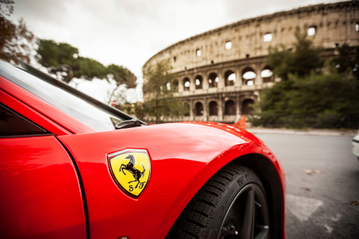 Rome, Italy - December 16, 2012: Details of a red Ferrari 458 Italia parked just in front of the Coliseum in Rome