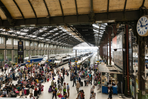 Paris, France - July 12, 2013: A large number of passengers waiting for trains at the Gare de Lyon Station.  High speed TGV trains can be seen parked in the background.