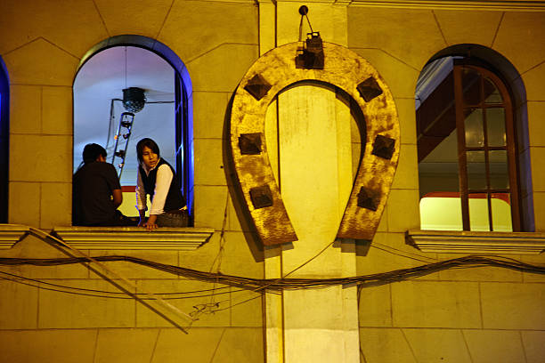 Arequipa, Peru - May 26, 2013: Peruvian couple at night in the city of Arequipa  sitting on an open upstairs windowledge and looking out into the street below
