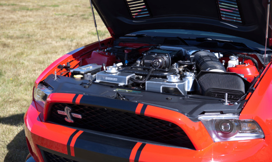 Arlington, United States - July 13, 2013: This image shows a beautiful red and black striped Shelby Cobra Mustang on display at a public car show.  Image highlights the powerful engine.