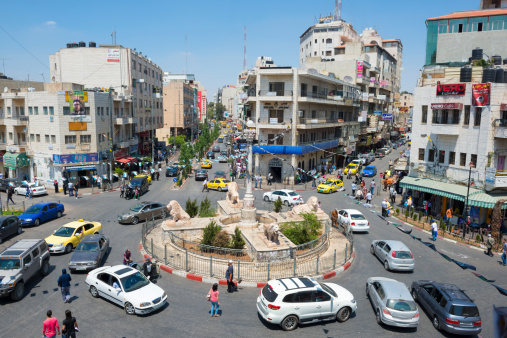 Ramallah, West Bank, Palestinian Territories - July 23, 2013: Traffic, pedestrians, and businesses at the Manara, the central traffic circle in downtown Ramallah. Located several miles north of Jerusalem, Ramallah is the seat of the Palestinian Authority government.