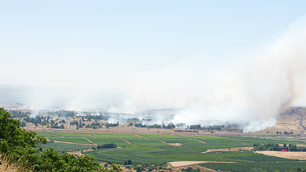 fogo e fumaça-guerra na síria, perto da fronteira de israel - qunaitira - fotografias e filmes do acervo