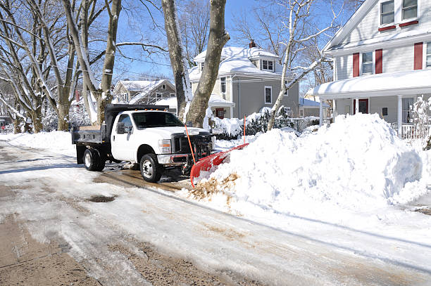 Plow Truck Cleaning Snow Filled Suburban NeighborhoodStreet Huntington, New York, USA - February 10, 2013: Plow cleaning neighborhood street after the February 8th blizzard hit the north east region of the USA dumping at least two feet of snow in the area. bare tree snow tree winter stock pictures, royalty-free photos & images