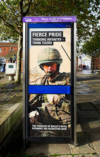 Army recruitment poster with graffiti Portsmouth, England - October 29, 2012: A British Army recruitment poster on a telephone box near Portsmouth Dockyard, with graffiti. The poster is recruiting for The Princess of Waless Royal Regiment and the graffiti says Why die for a country that doesnt care for you. (Background people.) british telecom photos stock pictures, royalty-free photos & images