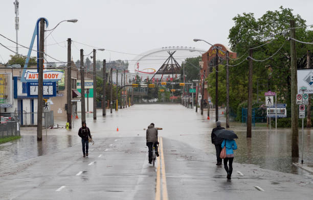 Residents Survey Flooded 17th Ave. Calgary, Canada - June 21, 2013: Residents don bicycles and umbrellas to survey the damage to a shutdown downtown. The east end of 17th Avenue and the Stampede grounds were some of the hardest hit areas due to their proximity to the confluence of the Bow and Elbow rivers. scotiabank saddledome stock pictures, royalty-free photos & images