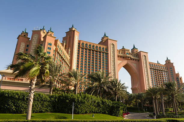 Atlantis The Palm Jumeirah Hotel Dubai, United Arab Emirates - January 11, 2013: A clear view of the famous luxury Hotel The Palm Atlantis in The Palm Island Jumeirah during a winter day. Many palm trees in foreground. One man is standing on the right. atlantis the palm stock pictures, royalty-free photos & images