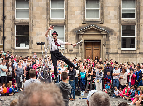 Edinburgh, Scotland, UK - August 3, 2013: A street performer balances on a tightrope, held up by volunteers picked from the crowd on the Royal Mile, on the first weekend of the Edinburgh Festival Fringe.