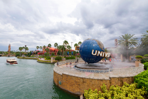 Orlando, USA - August 3, 2013: View of the entrance to the Universal Studios section in the Orlando resort, with the landmark globe sign in the foreground and visitor around it. Shoot on a cloudy summer day.