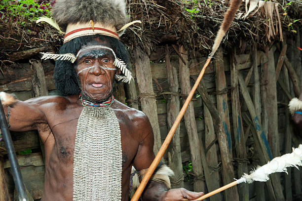 Dugum dani Leader Portrait Dugum Dani Village, New Guinea, Indonesia - June 20, 2012: Dani Warrior with a traditiona dresses and painting on a face solemnly welcomes guests. Dugum Dani Village.  The Baliem Valley Papua, Irian Jaya, Indonesian New Guinea dani stock pictures, royalty-free photos & images