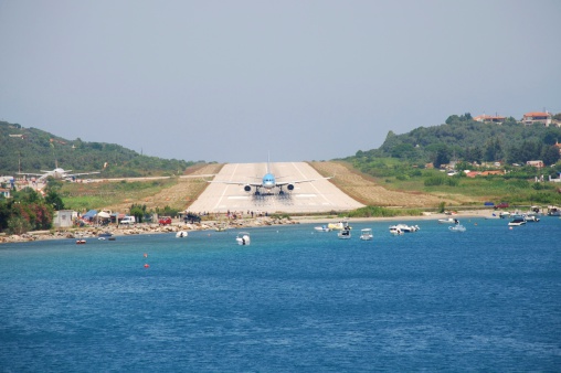 Skiathos, Greece - June 14, 2013: People watch a plane on the runway at Alexandros Papadiamantis airport on the Greek island of Skiathos. At just 5341 foot long, it is amongst the shortest runways in Europe.