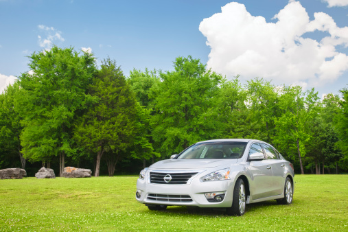 Nashville, Tennessee, USA - May, 15th 2012: A silver redesigned 2013 model year Nissan Altima four door car, parked in the grass of an empty field in Nashville TN.