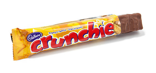 Crunchie Sponge Toffee Chocolate Candy Bar Unwrapped Toronto, Canada - May 10, 2012: This is a studio shot of a Crunchie sponge toffee candy bar made by Cadbury isolated on a white background. cadbury plc photos stock pictures, royalty-free photos & images