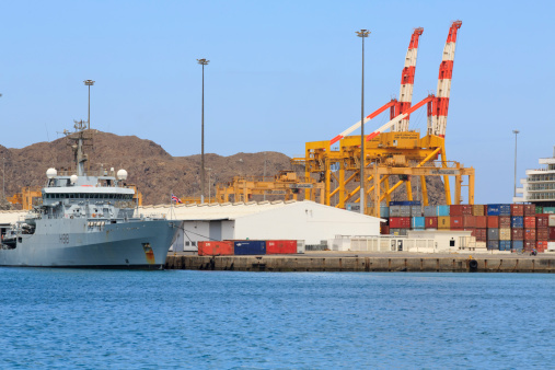Muscat, Oman - March 26, 2013: British frigate and container cranes