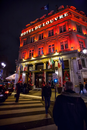 Paris, France  - December 26, 2012: Hotel du Louvre illuminated by night, Paris. 5 star Luxury Hyatt hotel, located in the heart of paris, Place AndrA Malraux. Main Entrance to the hotel. Few people outside. Christmas decorations at the entrance. People crossing the street.