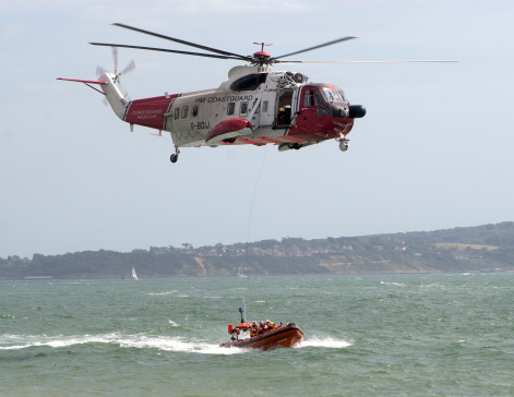 Lymington, United Kingdom - August 27, 2006: Air and Sea Rescue teams demonstrate their capabilities at in the waters of the Solent. The team are in the process of winching a man from the fast moving Lifeboat into the rescue helicopter.